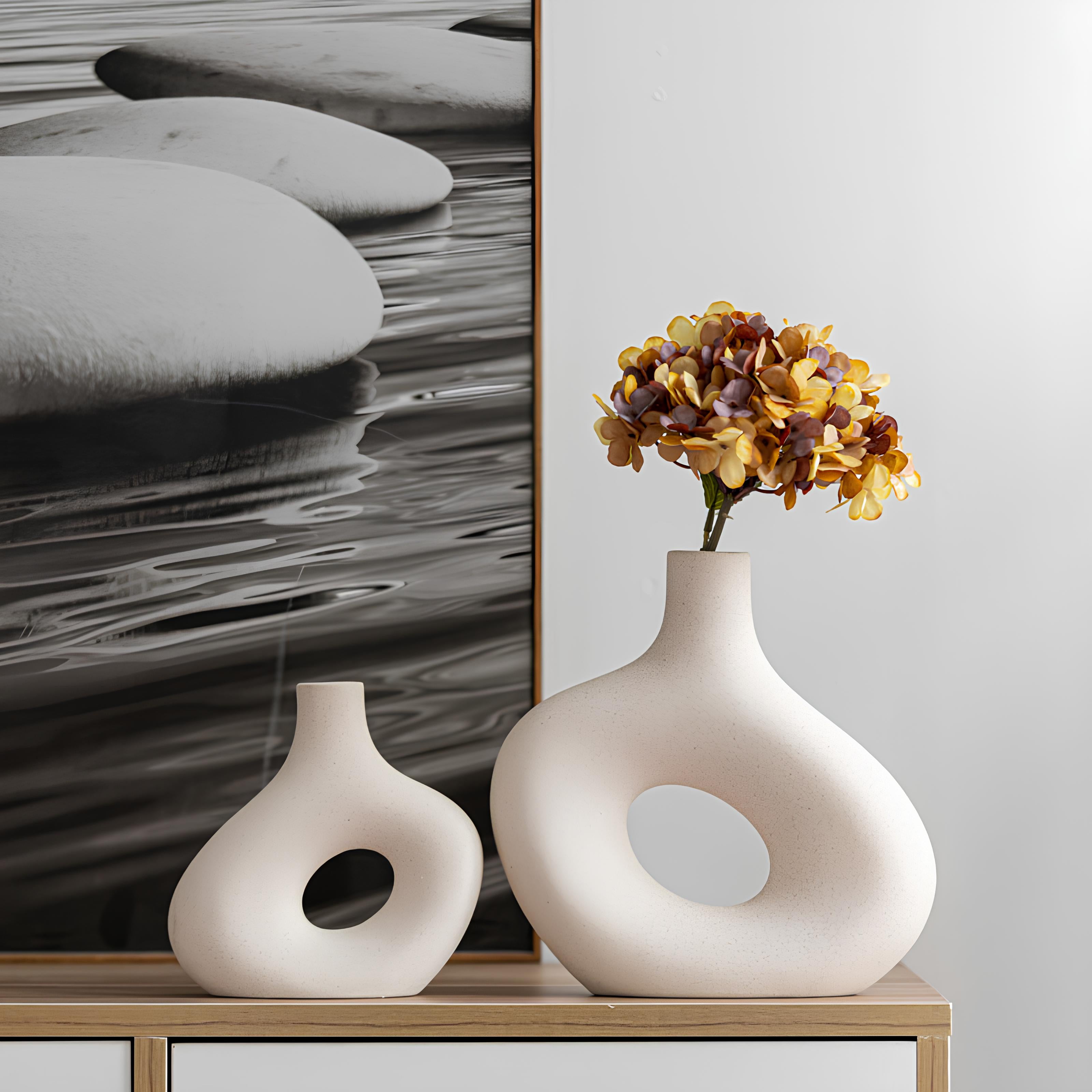 Two ceramic vases on a shelf with a piece of abstract art in the background.