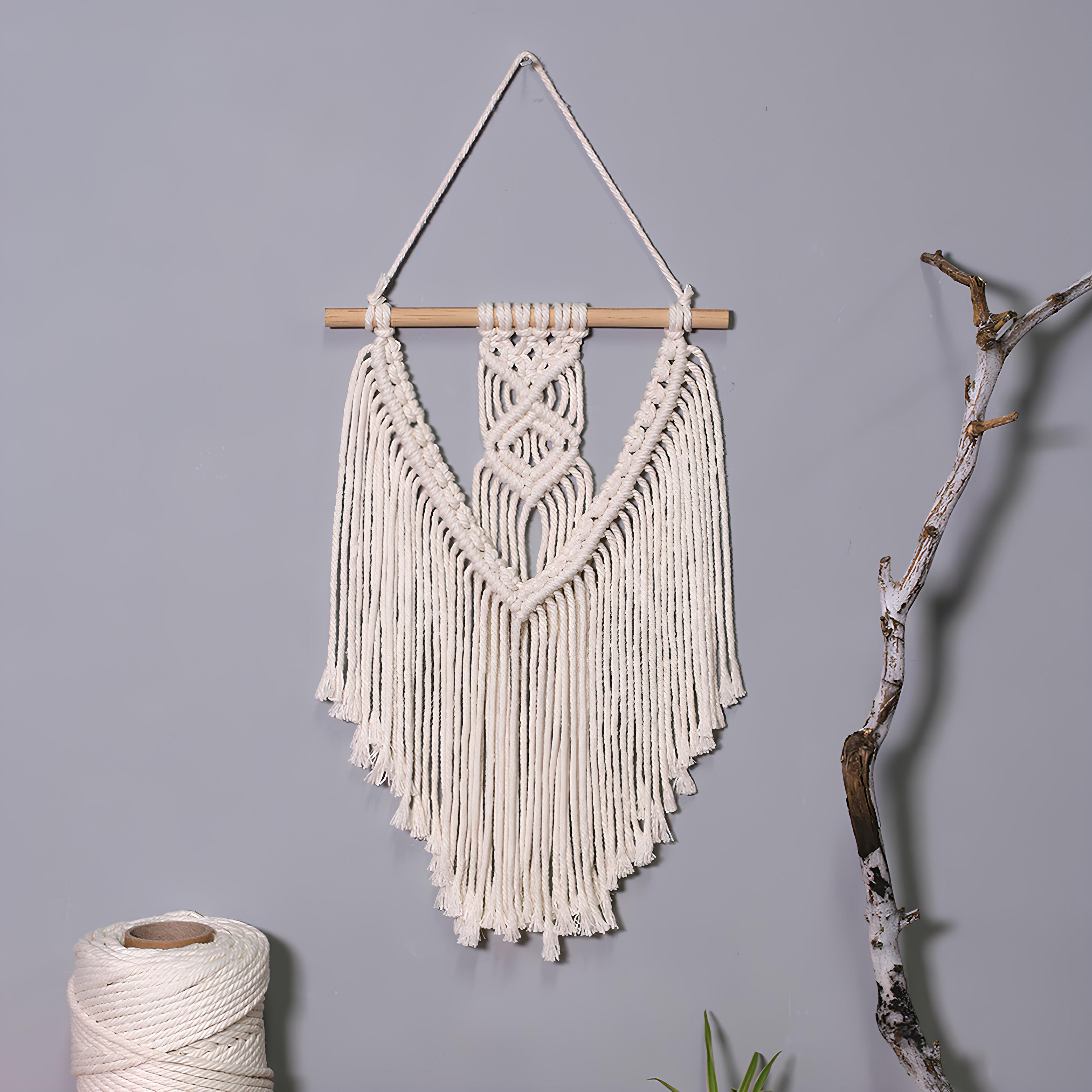 Macrame wall hanging with fringes on a gray background