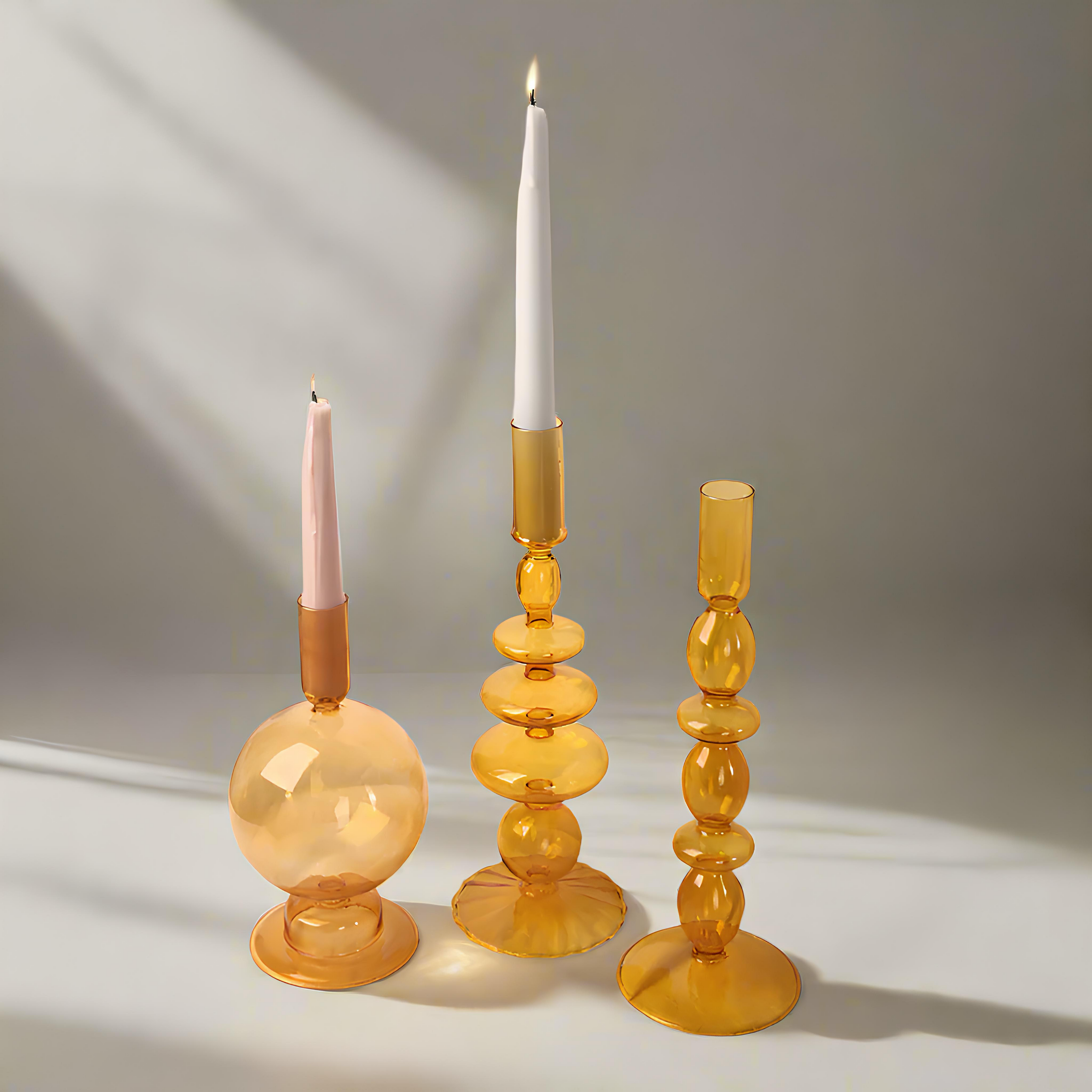 Three amber glass candle holders with candles on a neutral background