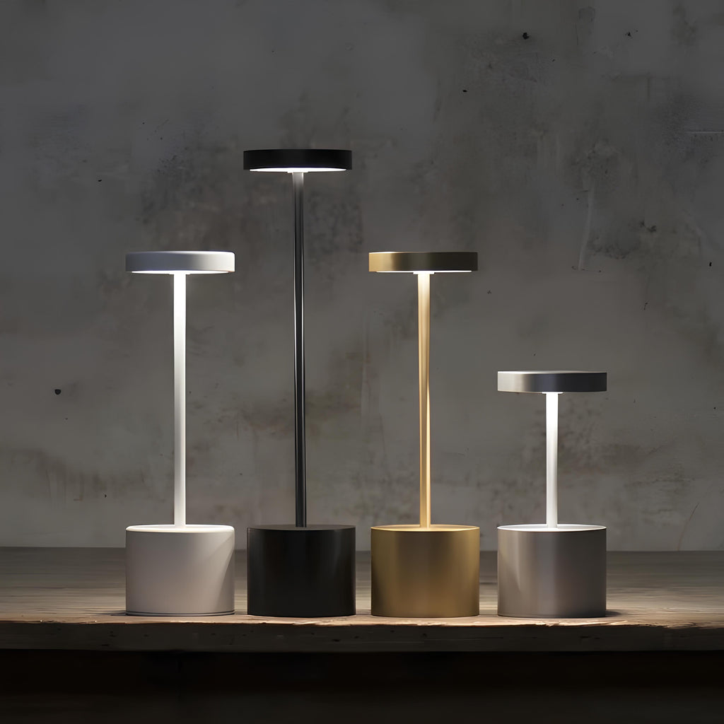 Set of five modern table lamps in different colors on a wooden surface with a concrete wall background.
