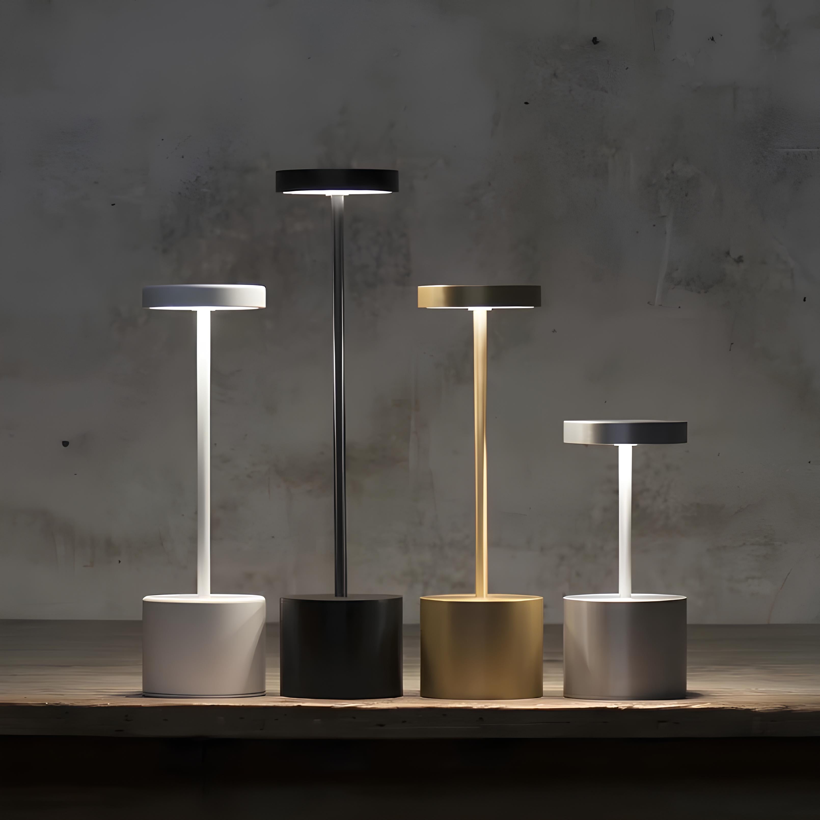 Set of five modern table lamps in different colors on a wooden surface with a concrete wall background.